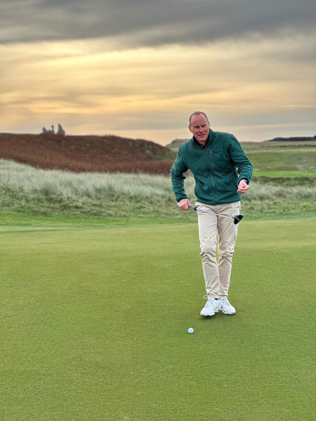 Robert Ashbrook on the practice green at sunset, holding a putter