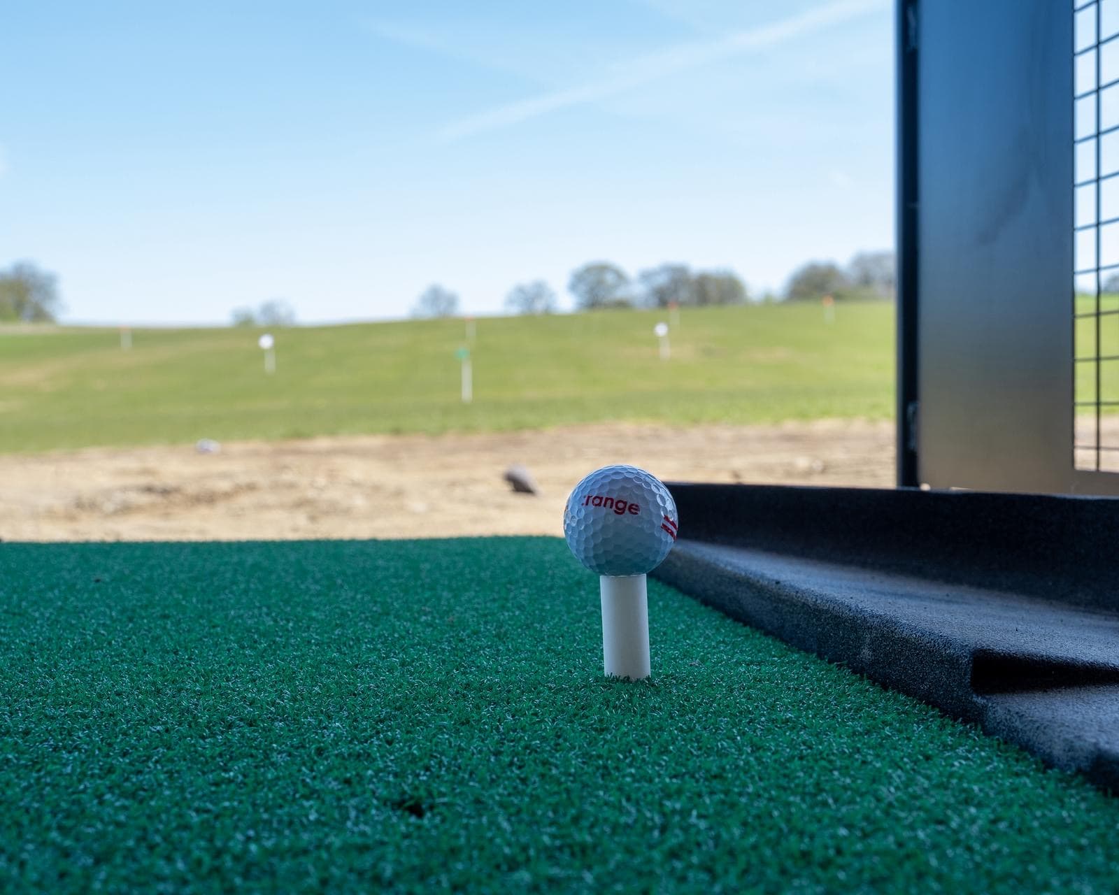 A range ball teed up at the bay with the practice field beyond — the starting point of every fitting